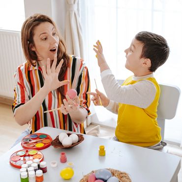 A woman and child painting Easter eggs together at a table.