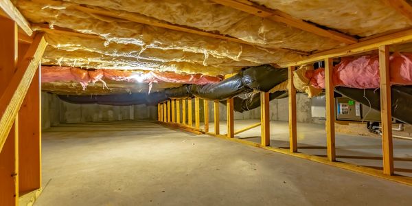Empty attic with insulation and wooden beams.