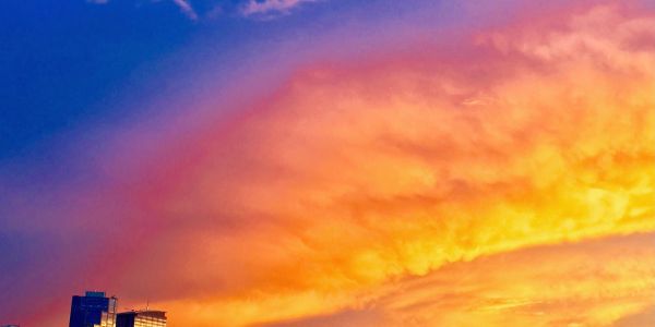 Vibrant sunset sky over city buildings with brilliant orange and blue hues.