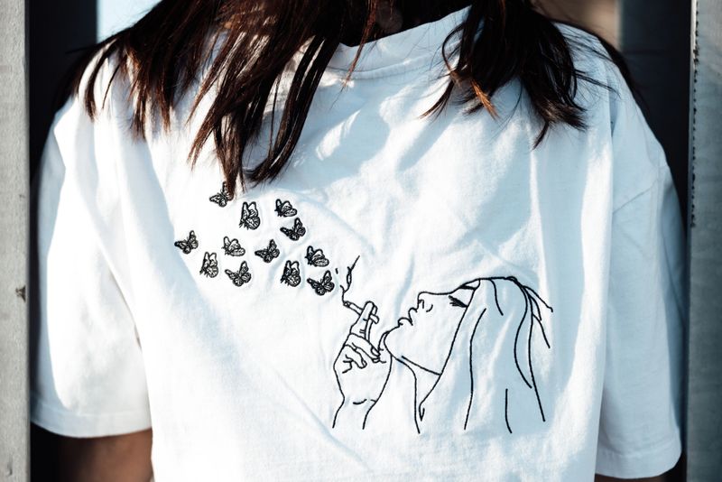 Young fashionable woman with fully property released handmade craft designer t-shirt standing outdoors. Detail of the handmade custom illustration Designer T-Shirt. Millennial Generation Female Young Fashion Design Portrait,
