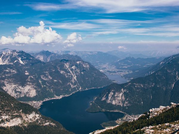 A serene lake surrounded by towering mountains under a blue sky.