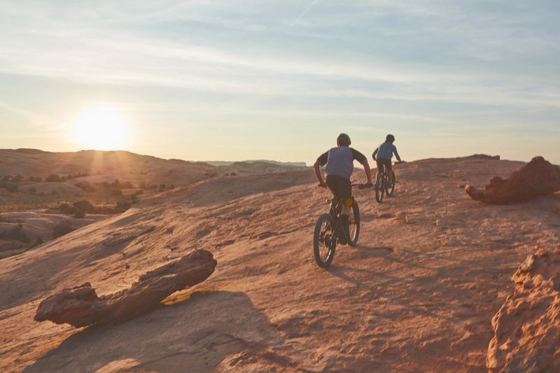 Full length shot of two young male athletes mountain biking in the wilderness