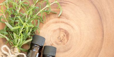 Botellas de aceite esencial con plantas sobre madera.
