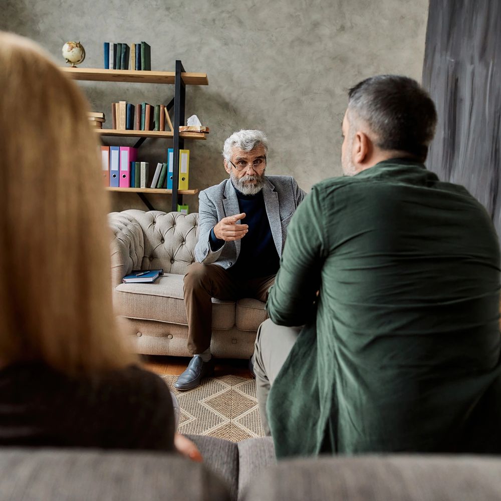 A therapist speaks with a couple during a counseling session.