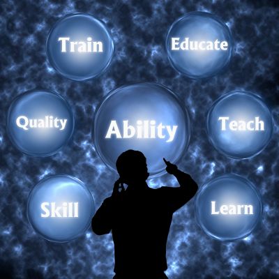 Silhouette of a person pointing at glowing bubbles with words on learning and skills.