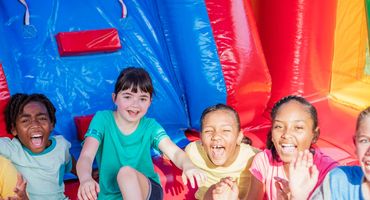 A group of joyful kids sitting on a colorful inflatable slide, laughing and having fun.