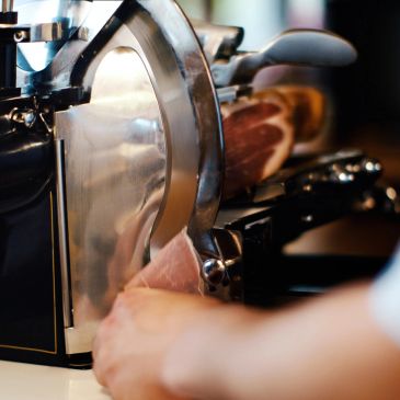 Ham slices being cut by a meat slicer.