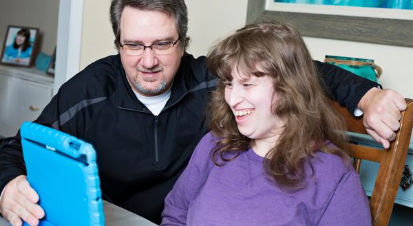A man and a woman smiling while looking at a tablet together.