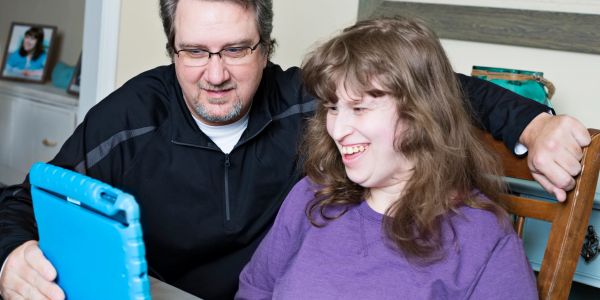 Man and woman smiling at a tablet.