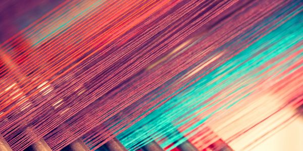 Colorful threads stretched on a weaving loom creating a vibrant pattern.