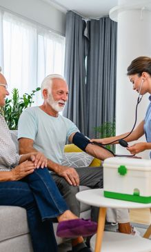 Nurse checking elderly man's blood pressure at home.