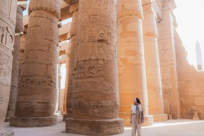 Tourist exploring ancient Egyptian temple columns.