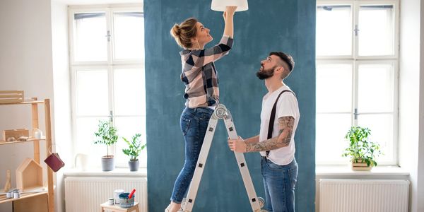 Couple fixing a light fixture indoors.