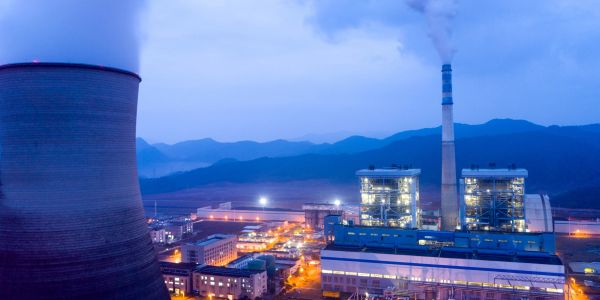 A power plant with cooling towers emitting steam at dusk.