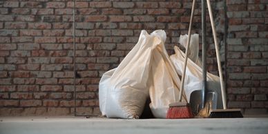 Bags and cleaning tools against a brick wall.