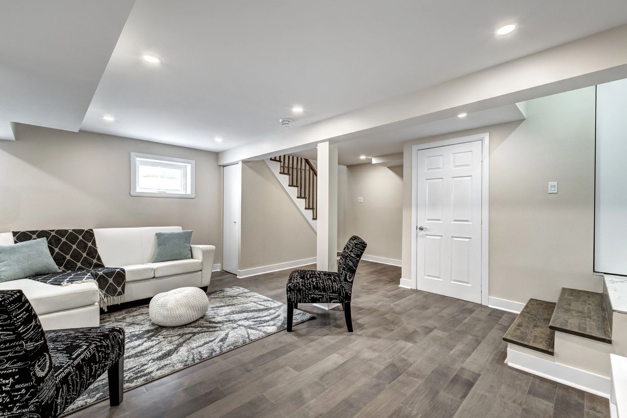 Bright basement living area with modern furniture and wooden flooring.