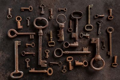 A collection of various old, rusty keys arranged on a dark surface.