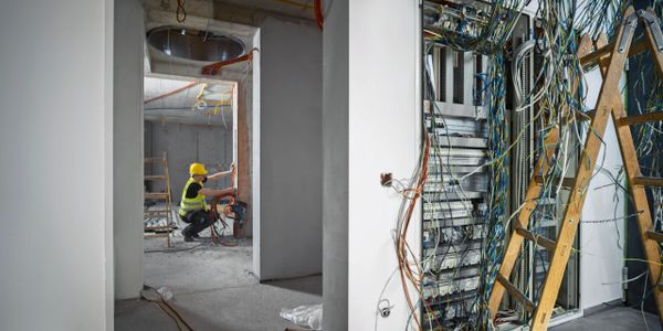 Electrician working on wiring in an unfinished building under construction.