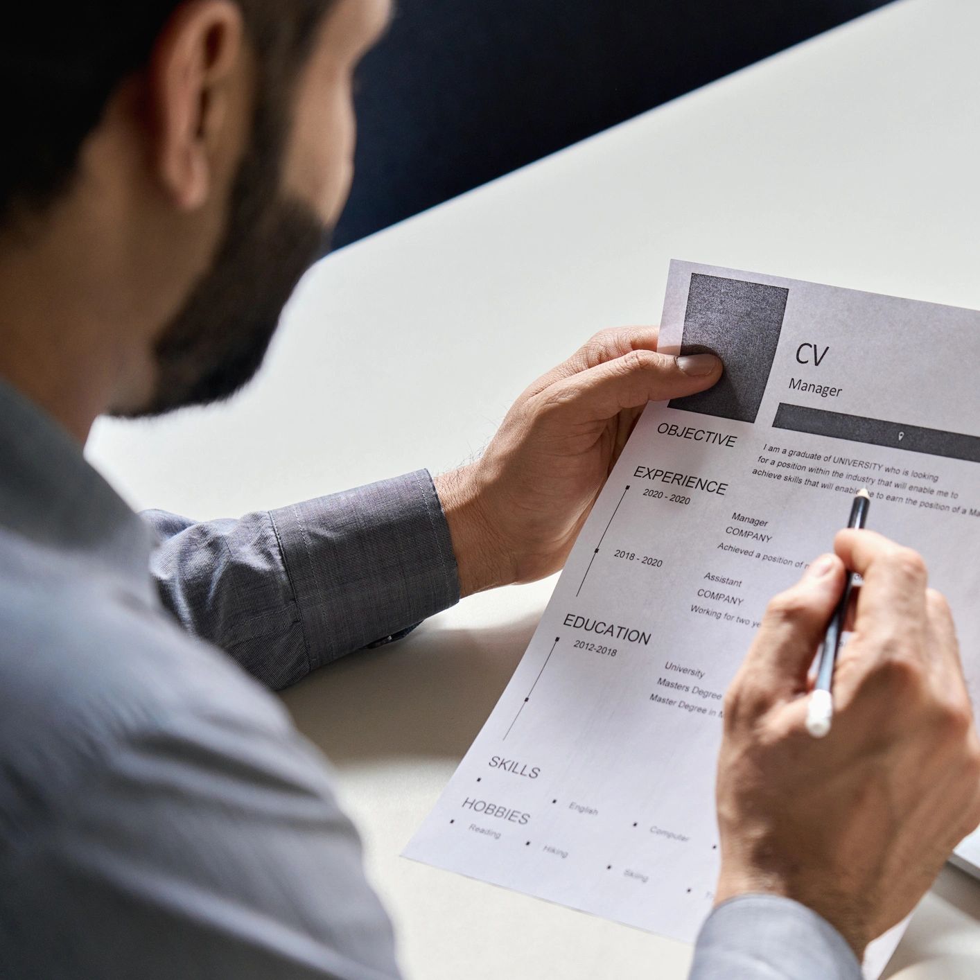 Man reviewing a CV with a pencil in hand.