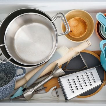 Top view of an organized kitchen drawer with various cooking utensils and pots.