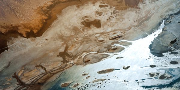 Aerial view of a barren landscape with brown and white patches.