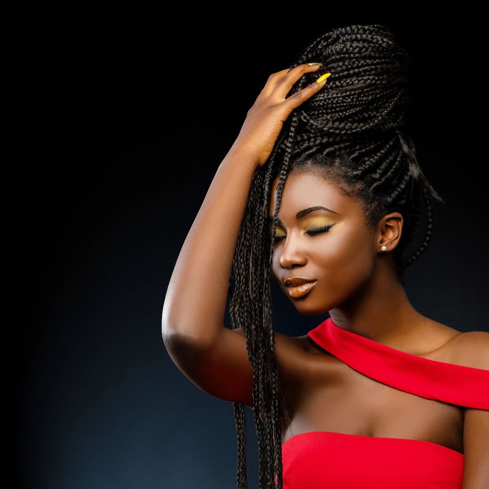 Elegant woman with braided hair and red dress against black background.