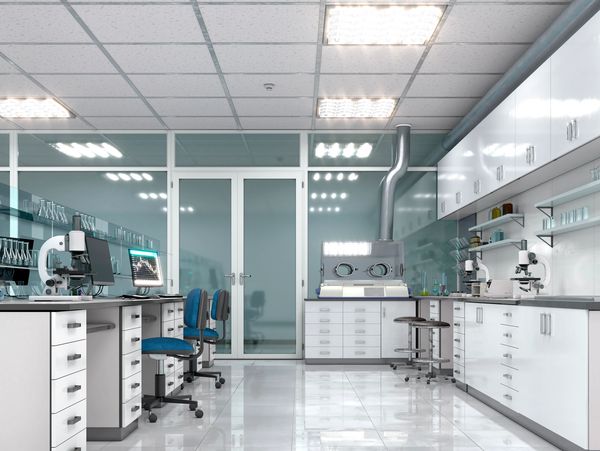 Modern laboratory with microscopes, glassware, and computers on white countertops.