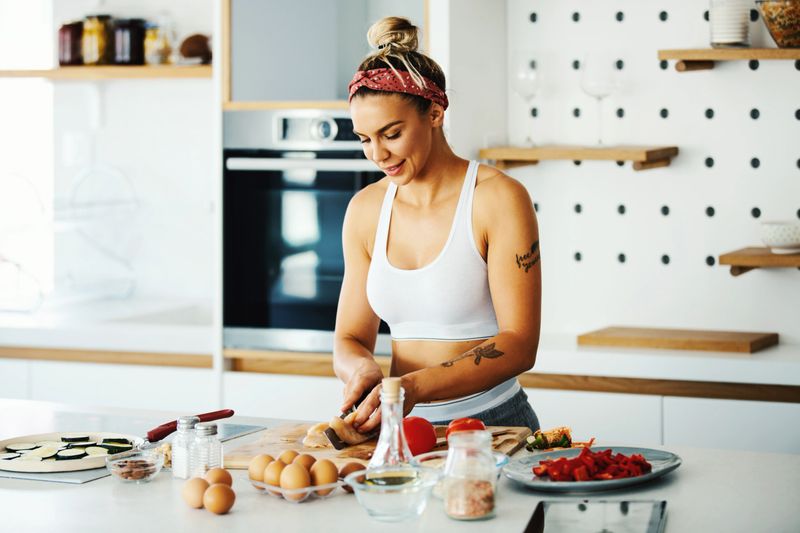 Young fit woman preparing meal in the kitchen.