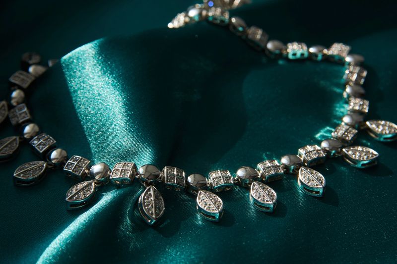 Elegant necklace with diamonds on green background with copy space. Women's platinum necklace with a precious gemstones, close-up. Elegant female jewelry