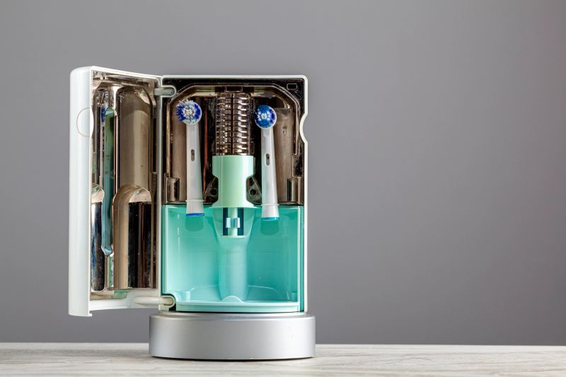 Interior of a UV light toothbrush head sanitizer with two brush heads inserted inside. The bulb in the middle produces strong ultraviolet light that kills germs on the items inside. The door is open.