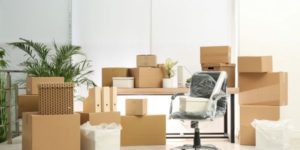 Office space cluttered with packed cardboard boxes and a chair.