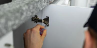 Person installing a cabinet hinge on a cabinet door.