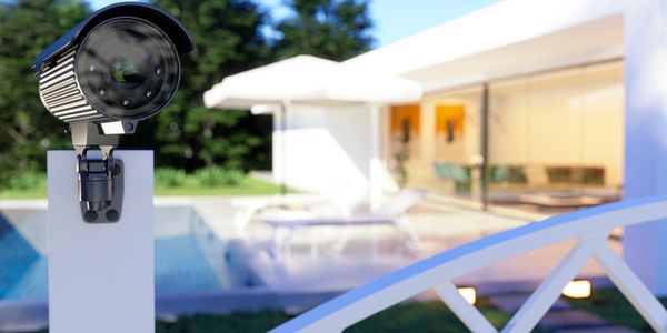 Security camera monitoring a modern home with a pool and patio.