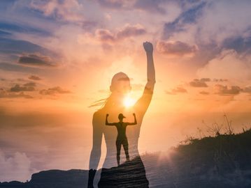 Silhouette of a woman raising her fist against a vibrant sunset, symbolizing strength and empowerment.