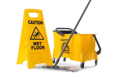 Yellow caution wet floor sign with mop and bucket for cleaning.