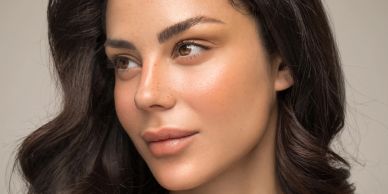 Close-up portrait of a woman with clear skin and dark hair.