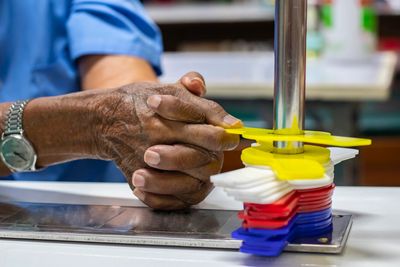 An elderly person doing a hand exercise with colored plastic grips.