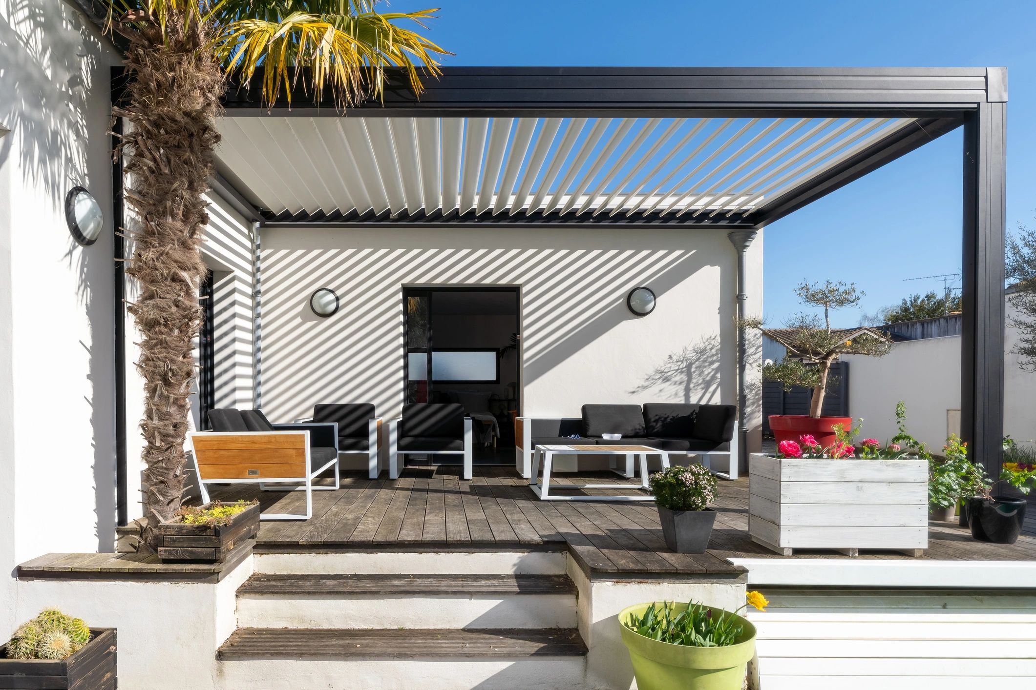 Modern patio with black furniture and pergola shading.