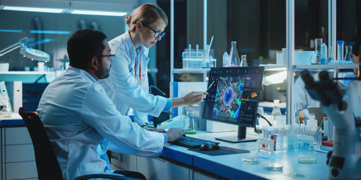 Scientists analyzing virus data on a computer in a lab.