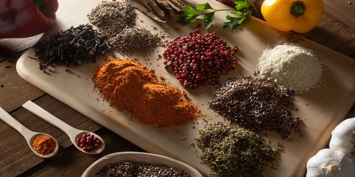 A wooden board with various spices and vegetables arranged neatly.