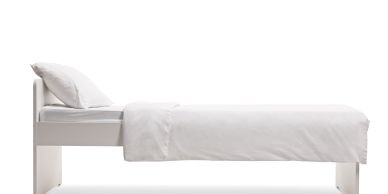 Cama individual blanca minimalista con ropa de cama blanca.