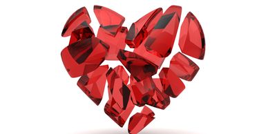 Red glass heart shattered into multiple pieces on a white background.