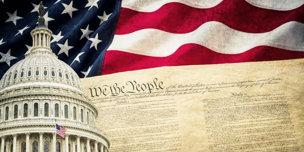 The U.S. Capitol dome, American flag, and Constitution symbolize American democracy.
