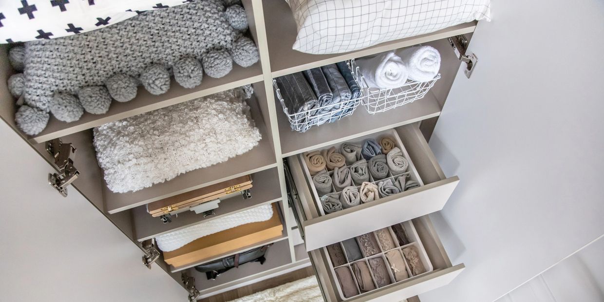 Neatly organized wardrobe with folded clothes and towels in drawers and shelves.