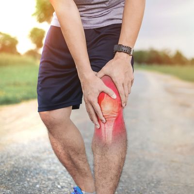Person holding knee in pain during outdoor activity.