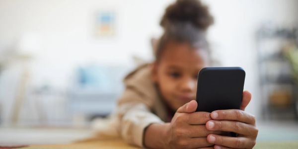 Child holding a smartphone lying on the floor.