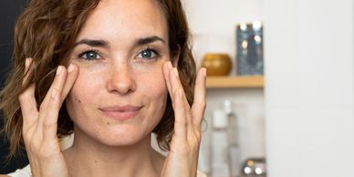 Woman gently touching her face with a calm expression.