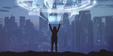 Silhouette of a person interacting with futuristic digital holograms above a cityscape.