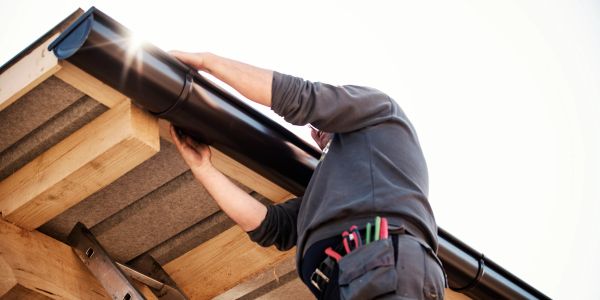 Person fixing a gutter on a roof.