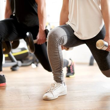 People exercising with dumbbells in a gym.